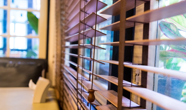 Kobieta wygląda przez okno z&nbsp;żaluzjami